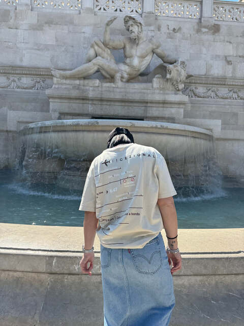 Cliente indossa la TravelTee davanti a una fontana, foto reale