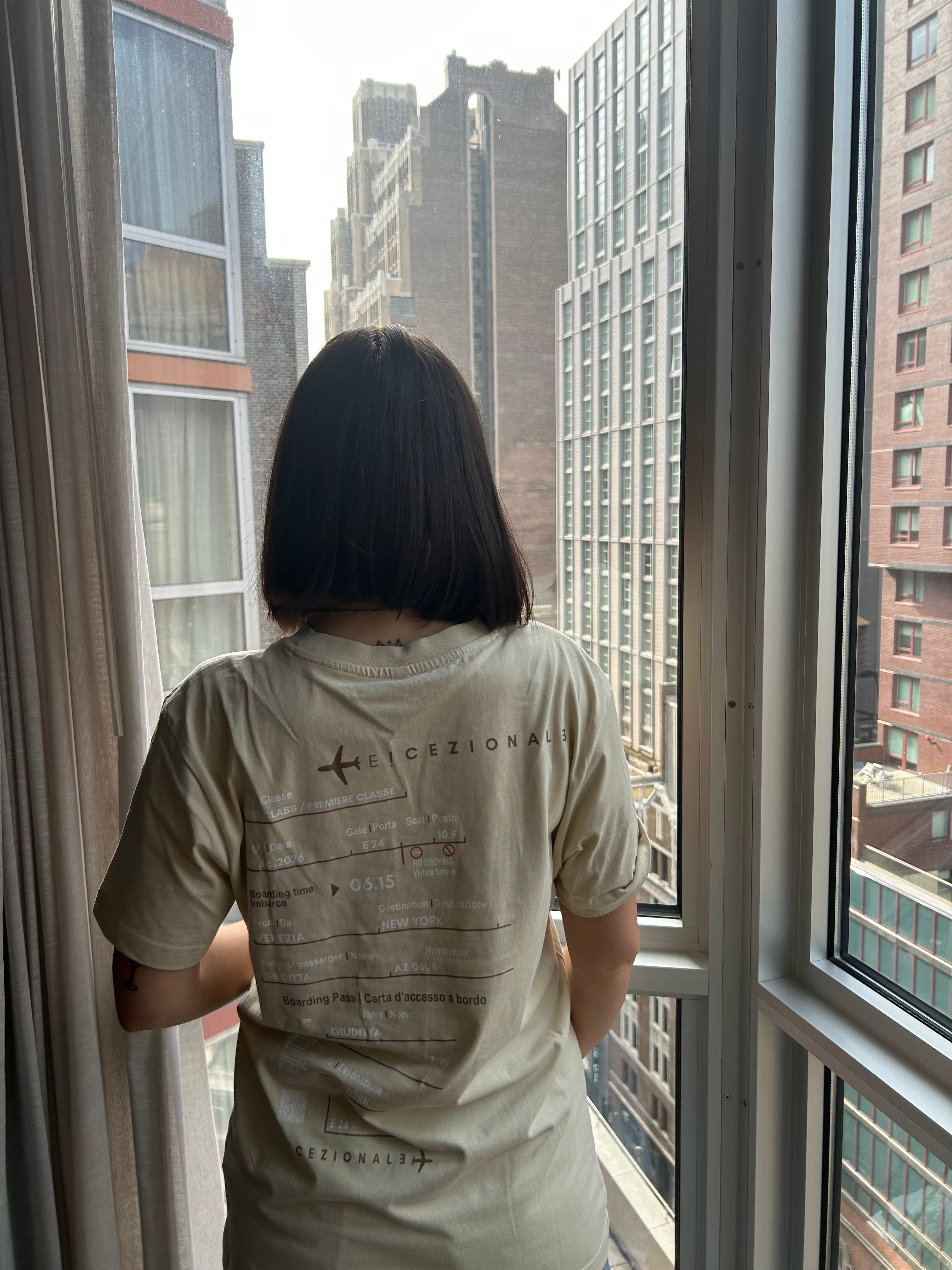 Cliente indossa la TravelTee Beige a New York, vista dalla finestra, foto reale