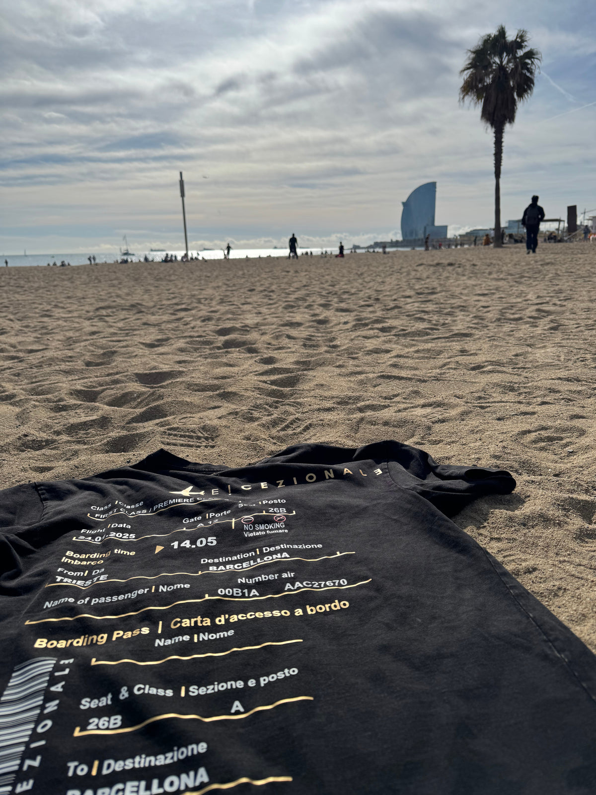 Cliente indossa la TravelTee Nera acidwash in spiaggia a Barcellona, foto reale